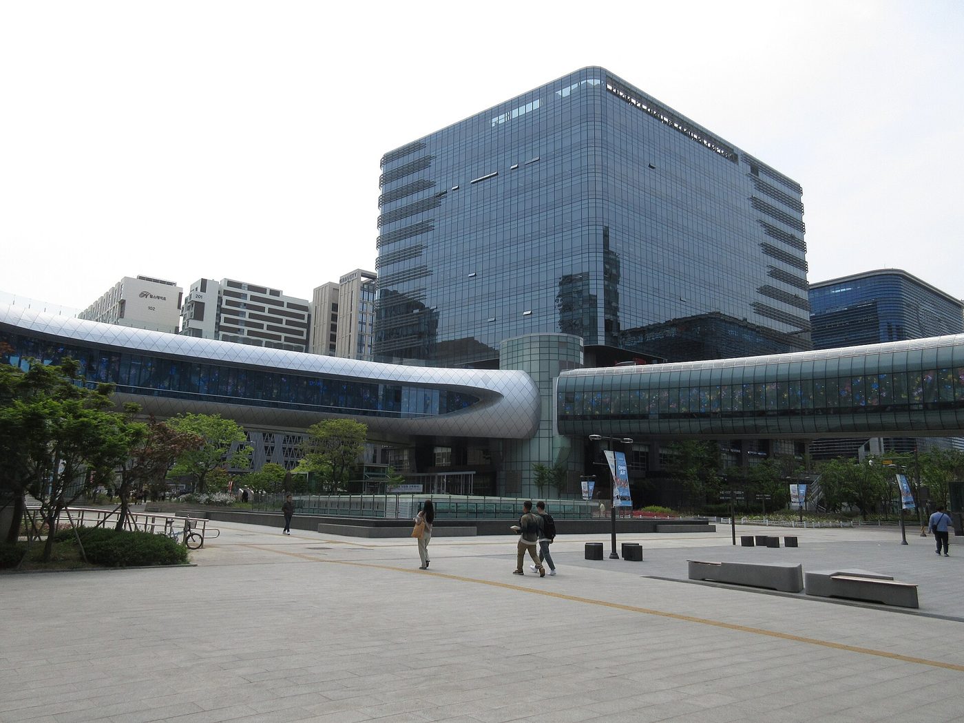 판교역 광장에서 본 알파돔시티. 좌우로 이어지는 곡면 유리의 공중보행통로 컬쳐밸리와 그 뒤의 유리 오피스, 왼쪽 원경에 힐스테이트 판교역